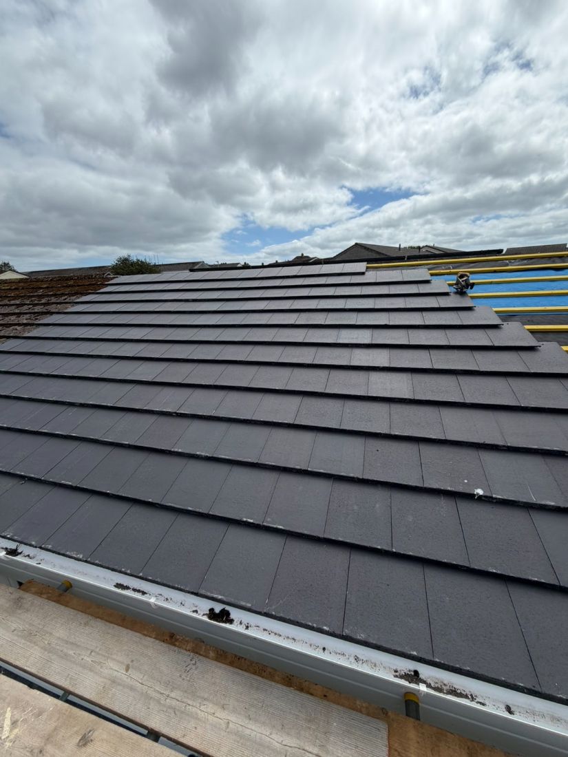 A completed pitched roof re-covered edge to edge in new dark grey tiles